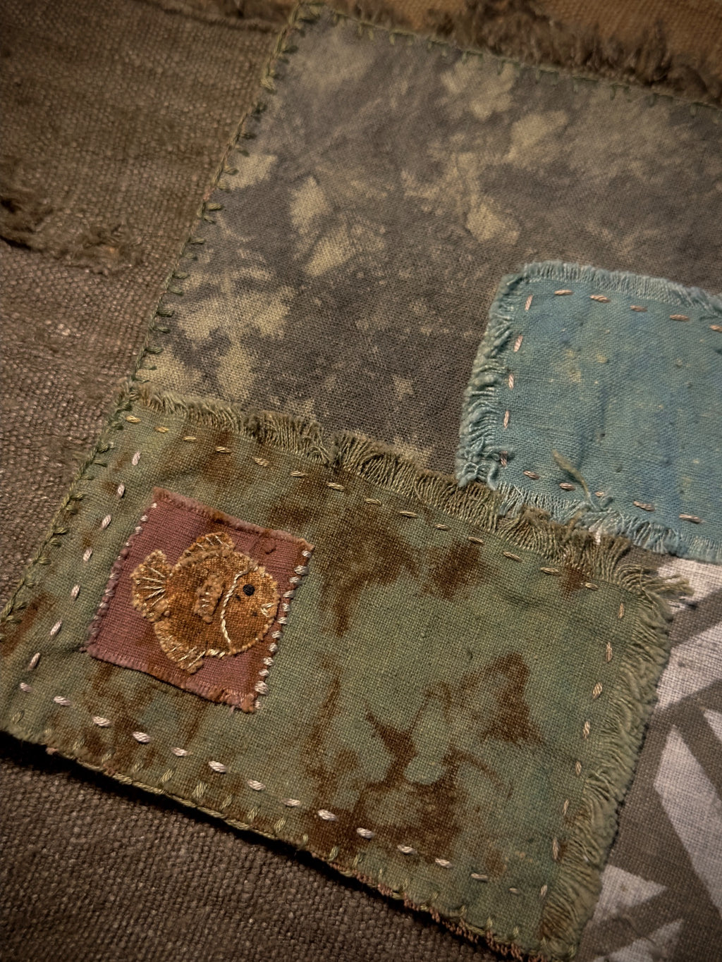 Close-up of embroidered fish and hand-stitched plant-dyed fabric