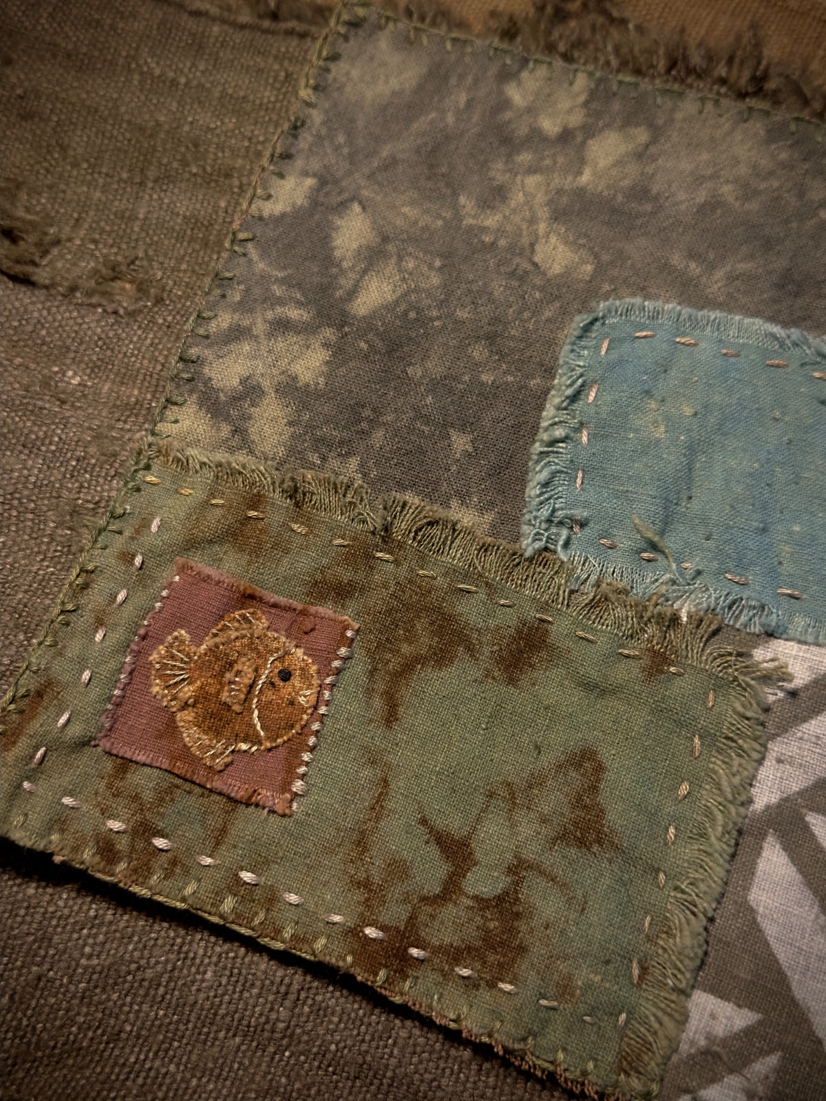Close-up of embroidered fish and hand-stitched plant-dyed fabric