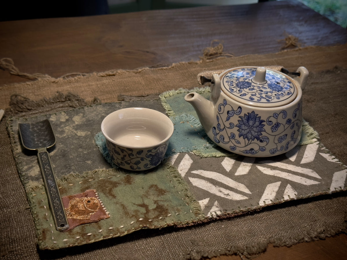 Tea mat in use with teapot, cup and tea utensil